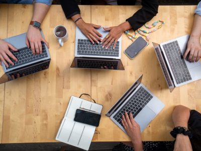 Mains de 4 personnes qui travaillent sur leur ordinateur